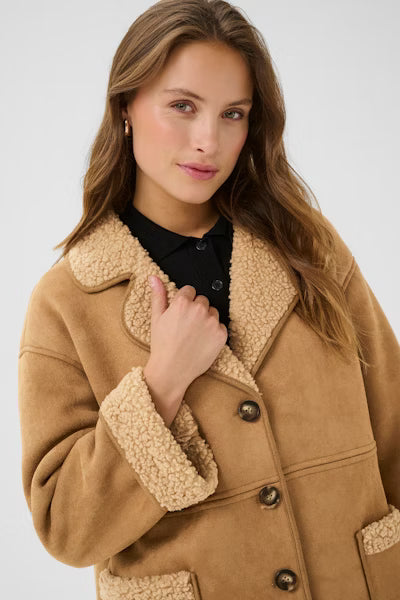 Woman wearing a brown coat with sherpa lining on a plain background