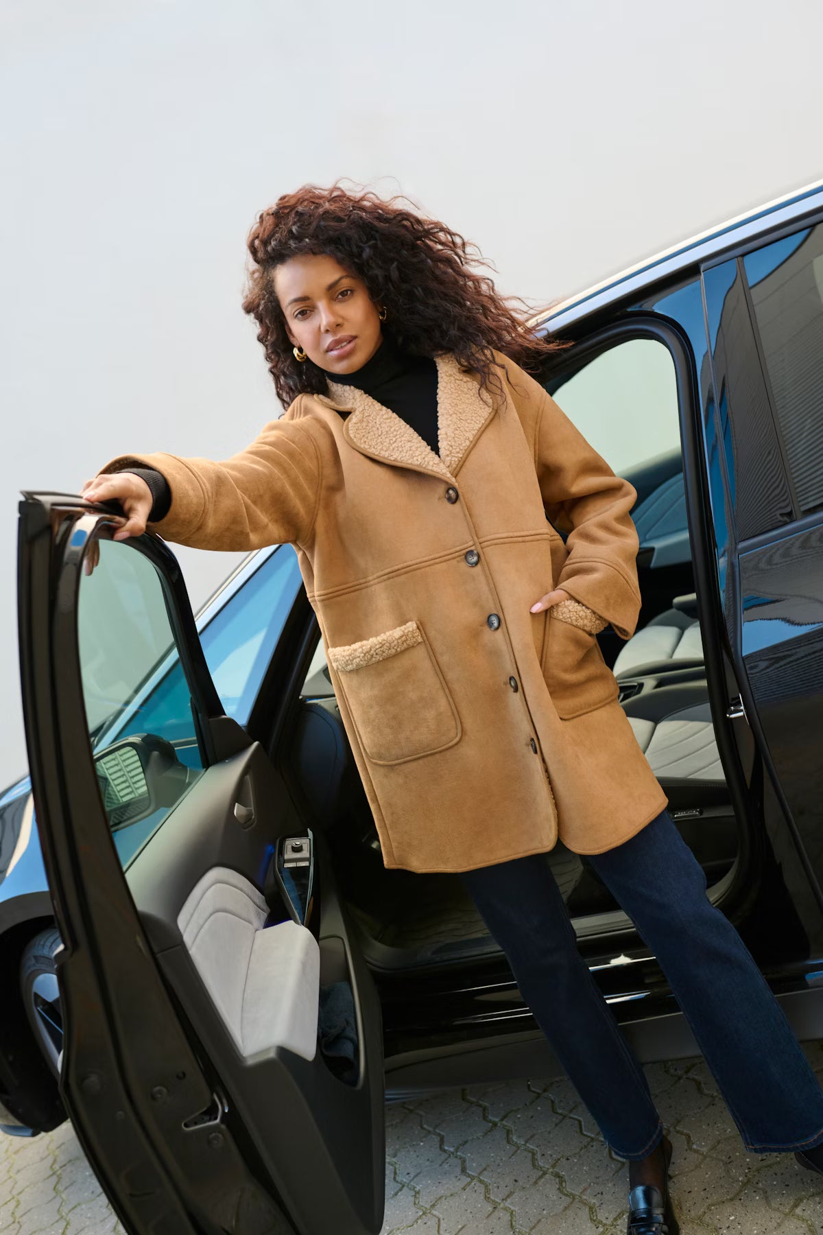 Woman in a tan coat getting out of a car
