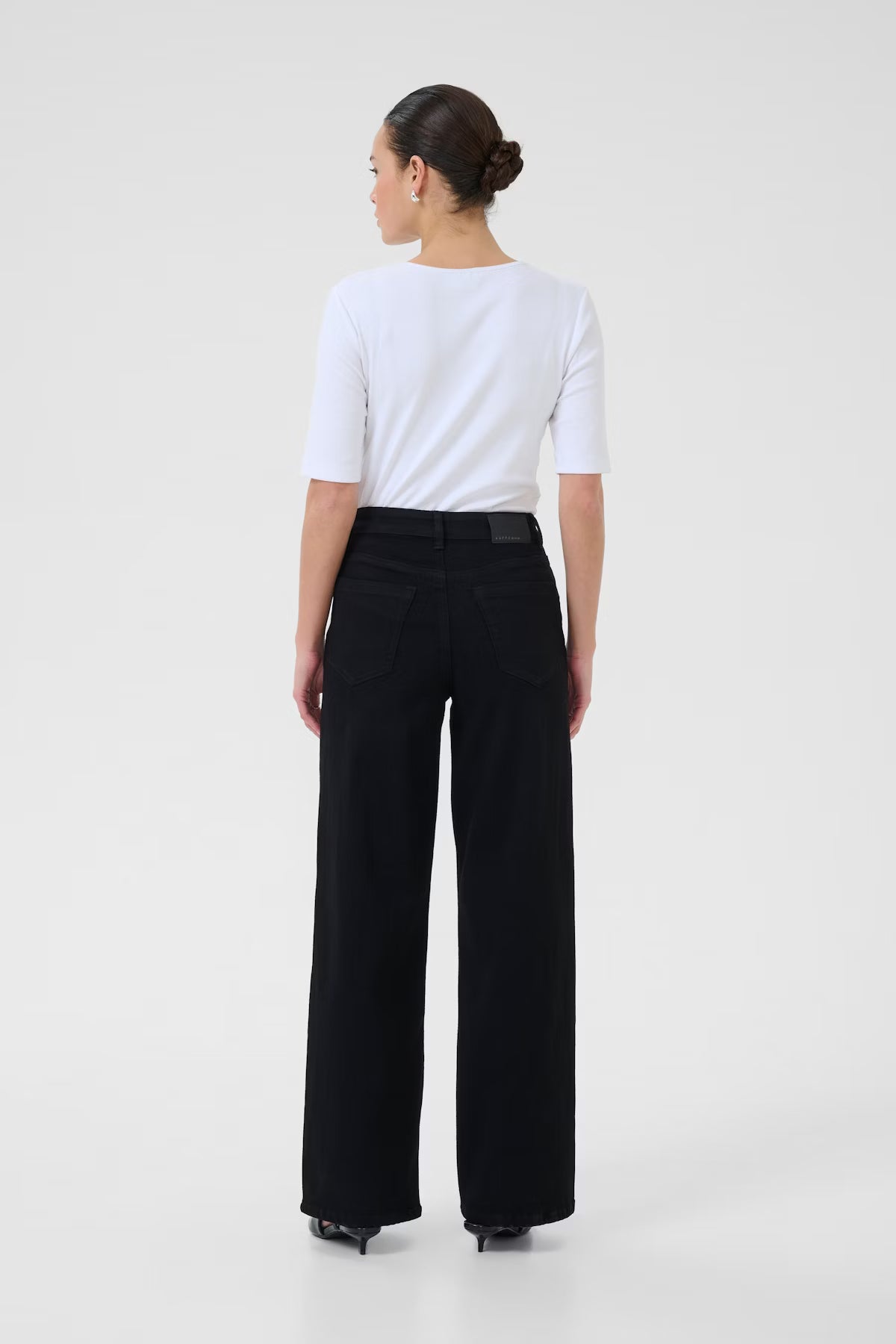 Person wearing a white top and black jeans on a white background