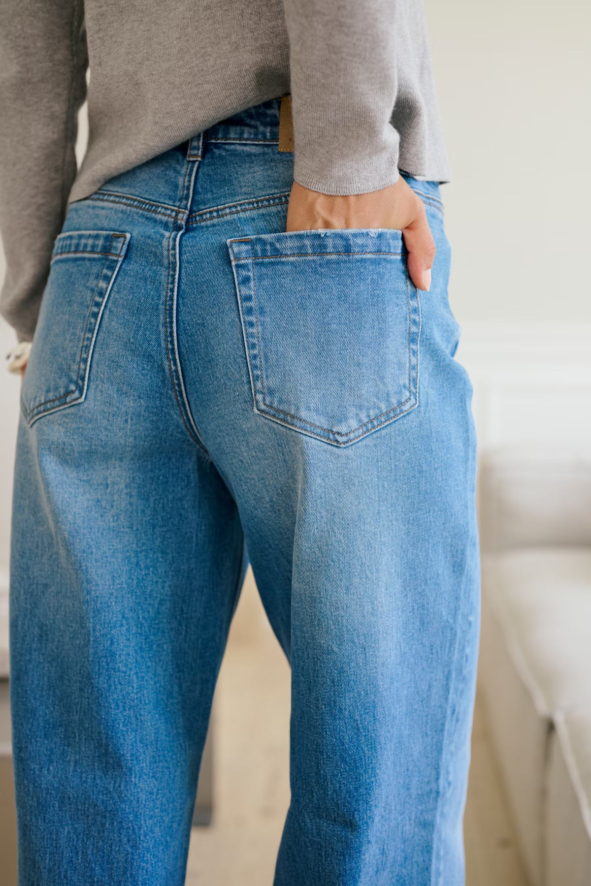 Person wearing blue jeans with a neutral background