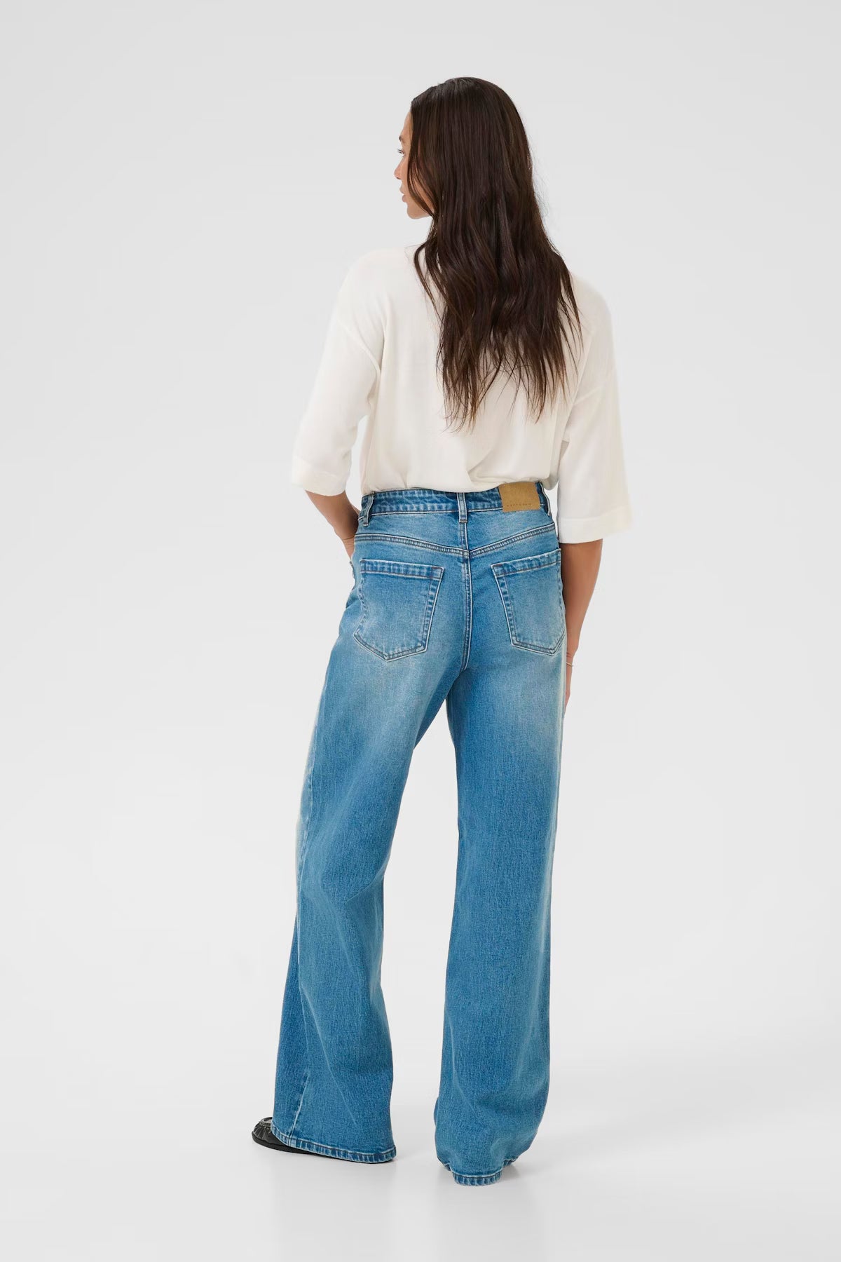 Person wearing blue jeans and a white shirt on a white background