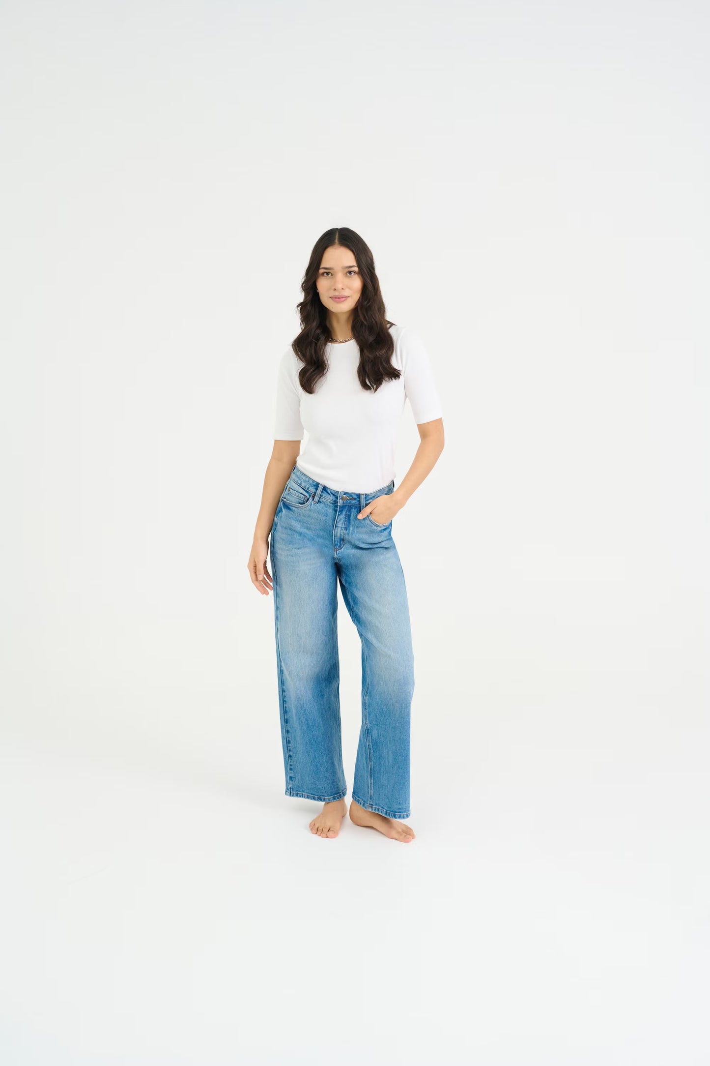 Woman wearing a white shirt and blue jeans on a white background