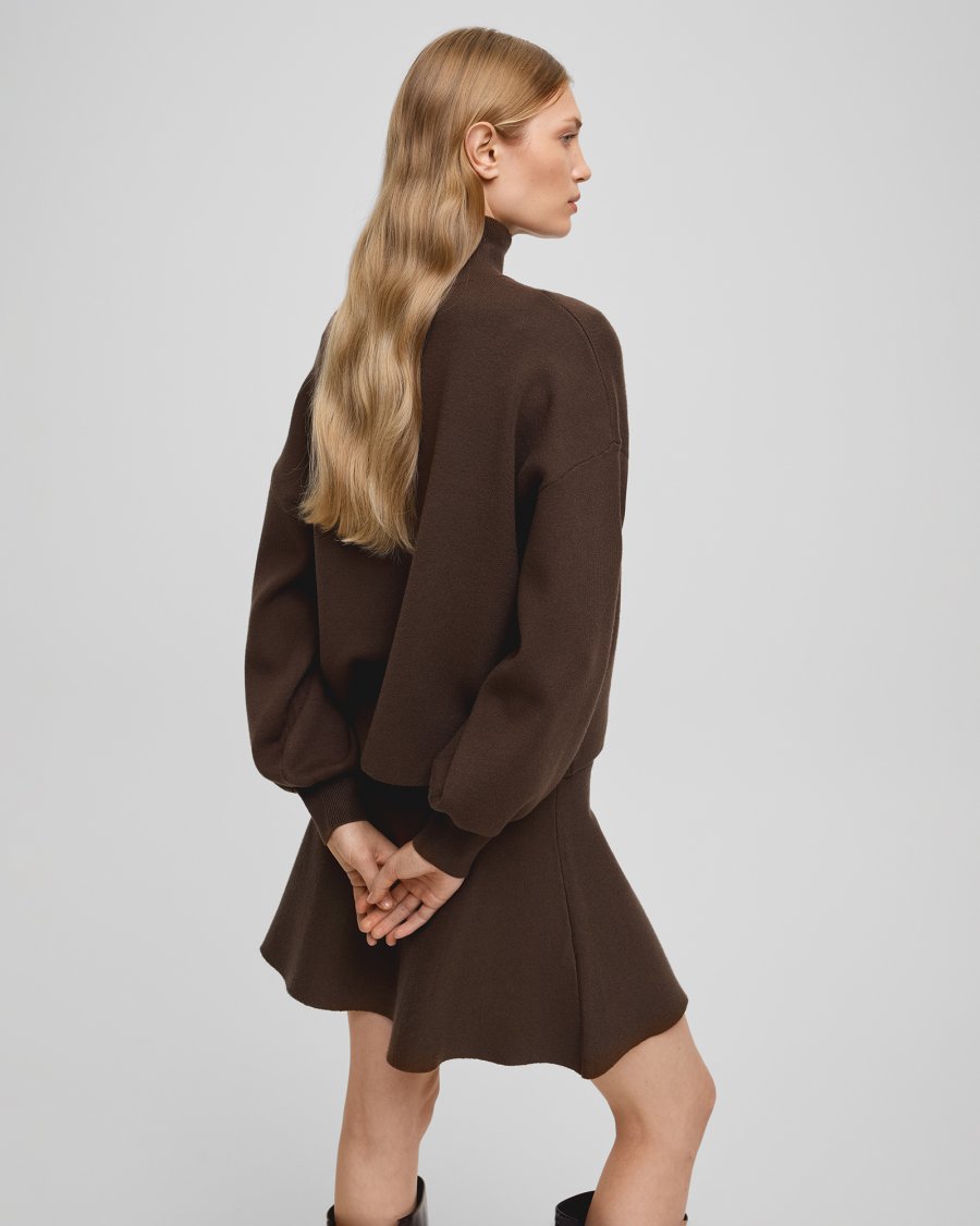 Woman wearing a brown dress against a plain background