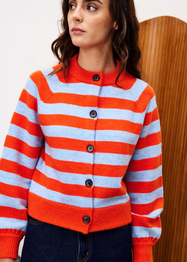 Woman wearing a red and blue striped sweater with black buttons against a wooden background