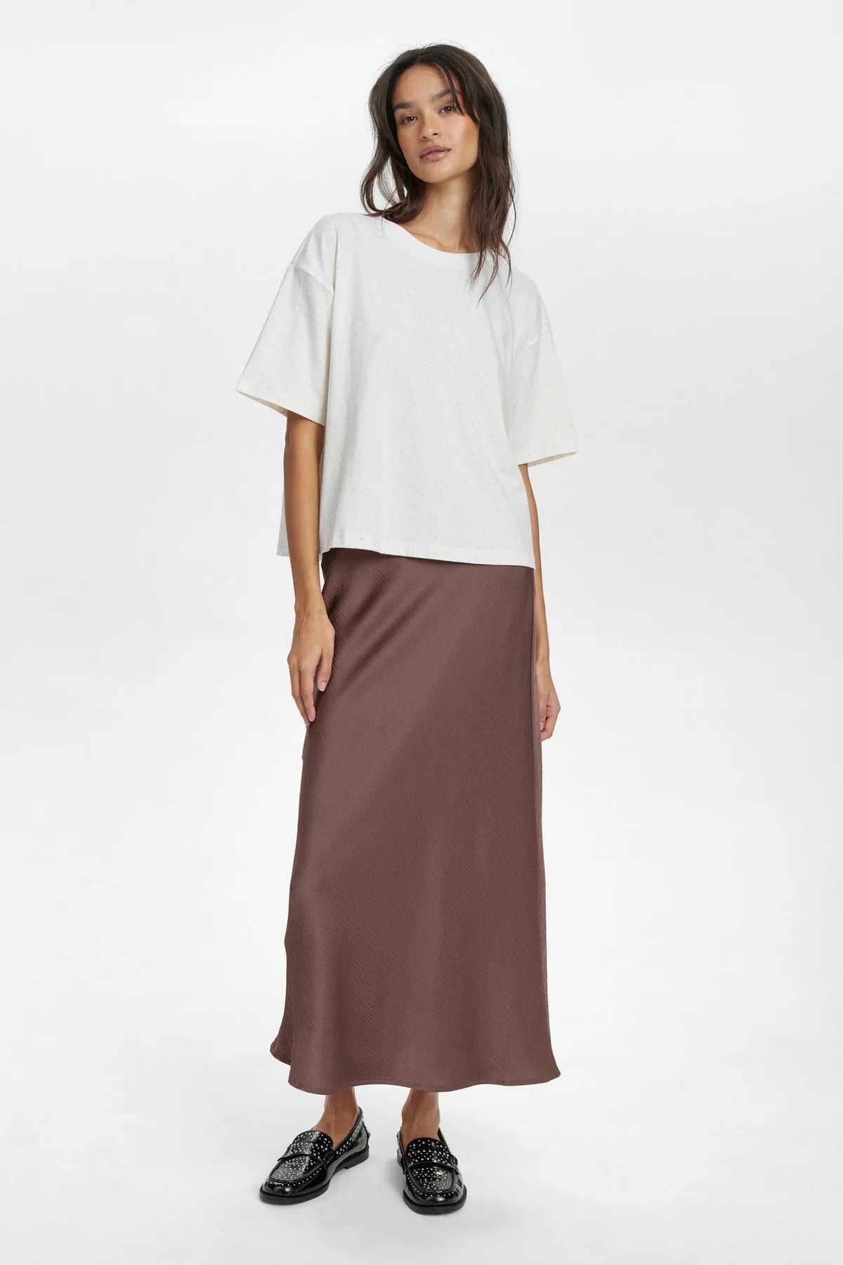 Woman wearing a white top and brown skirt on a white background