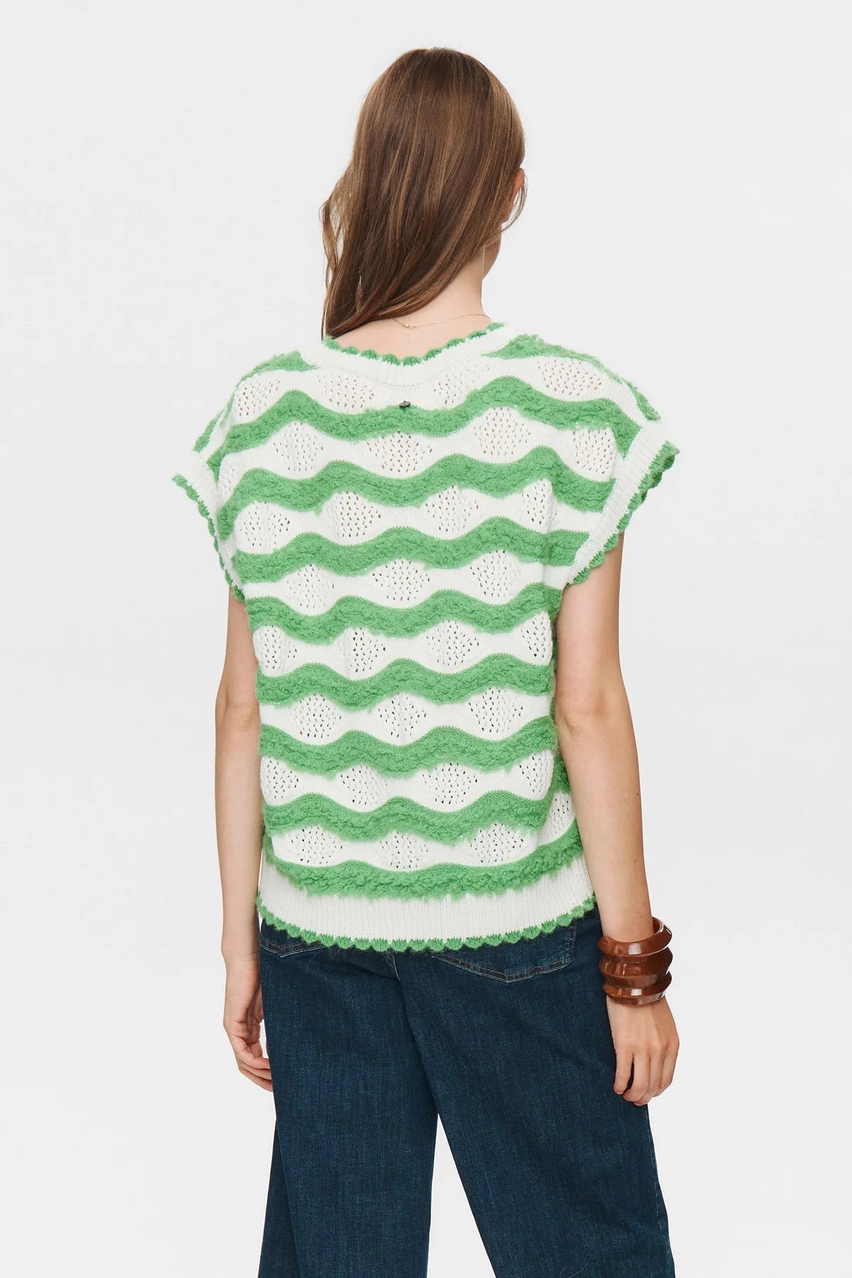 Person wearing a green and white patterned top on a plain background