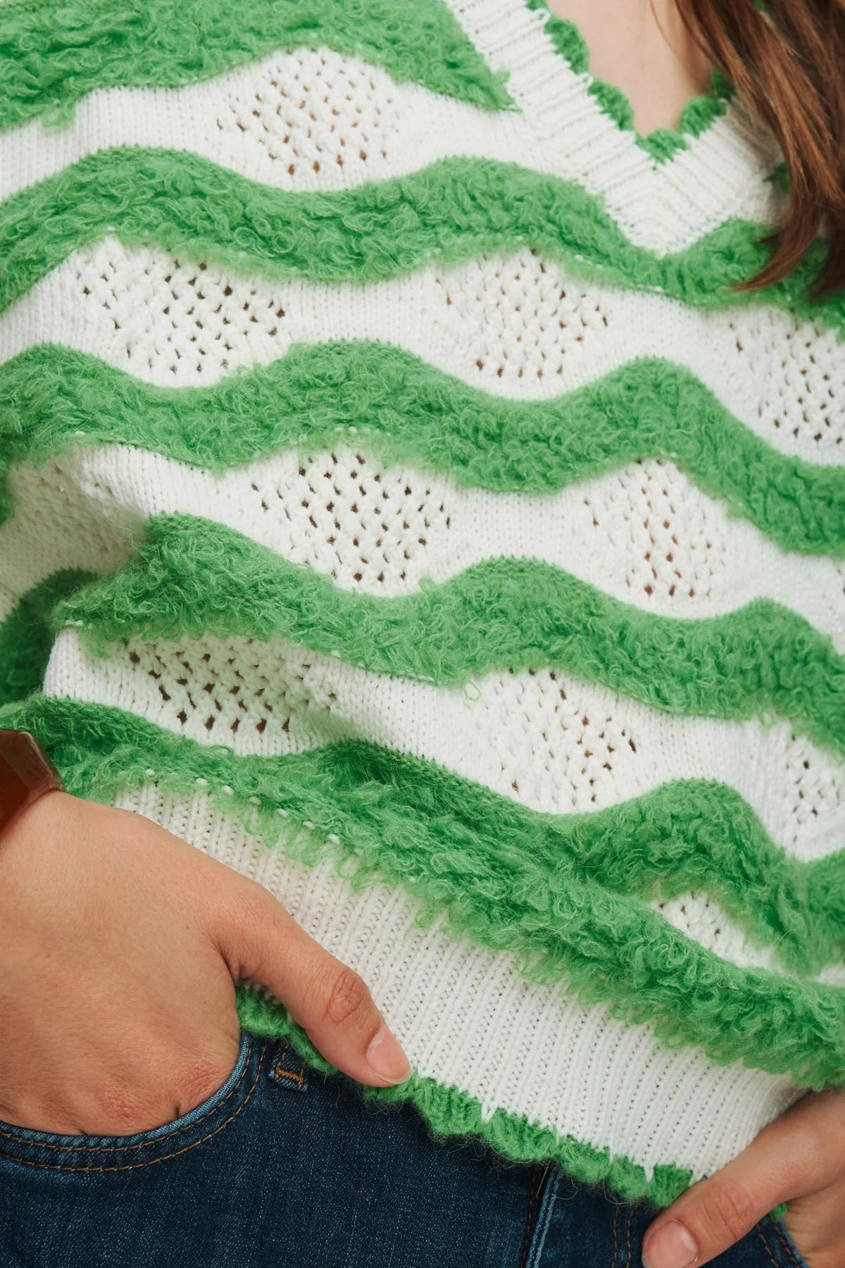 Close-up of a green and white knitted sweater with wavy pattern.