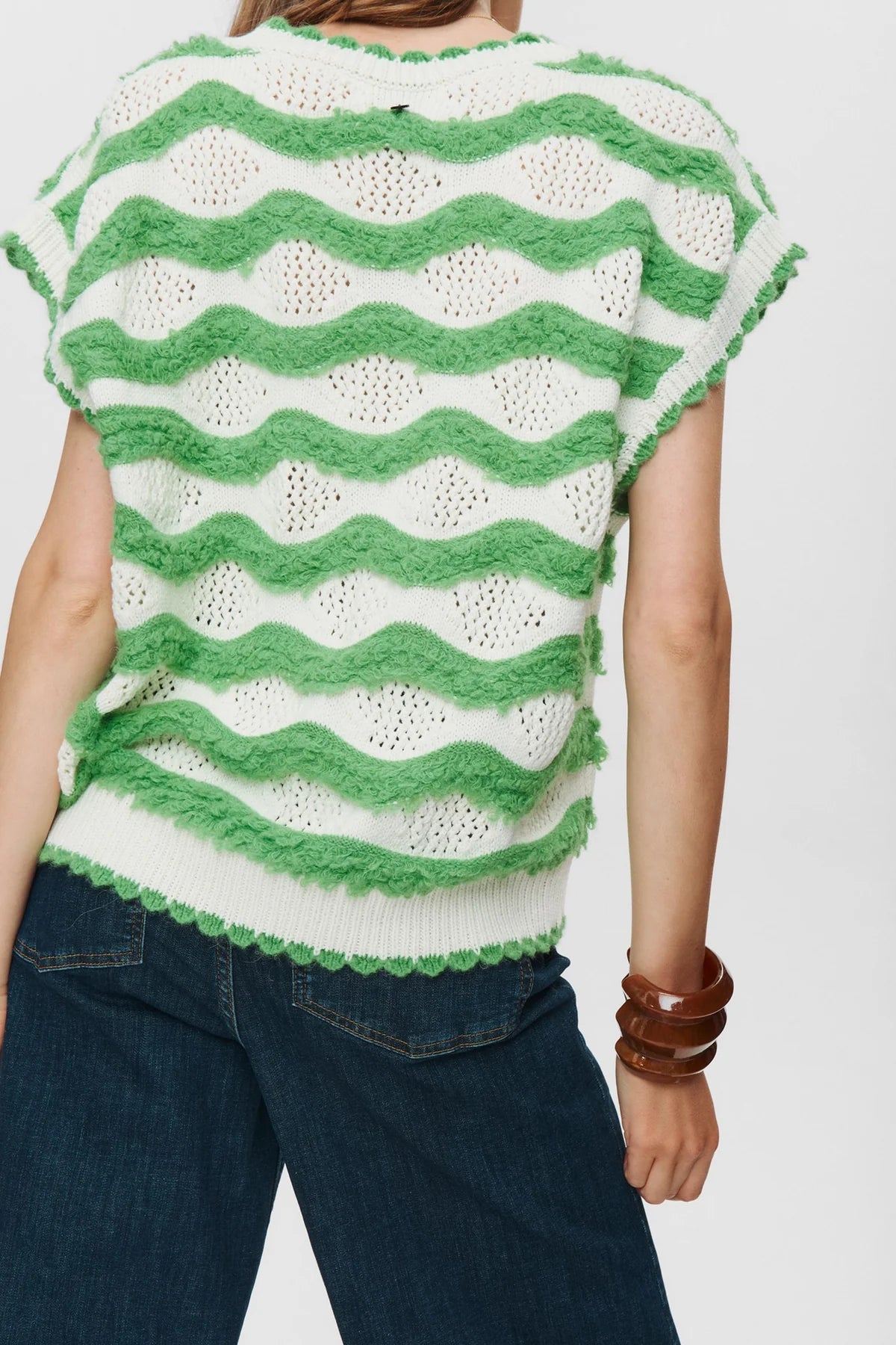 Green and white striped sleeveless top worn by a person on a plain background