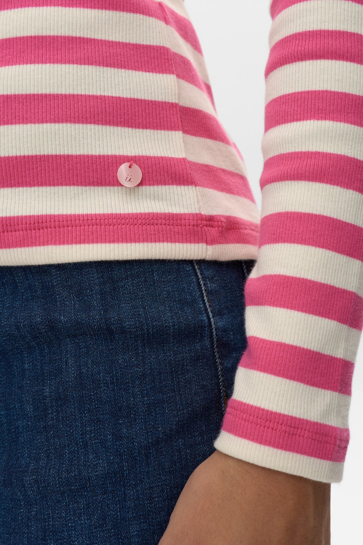Close-up of a person wearing a pink and white striped shirt with blue jeans.