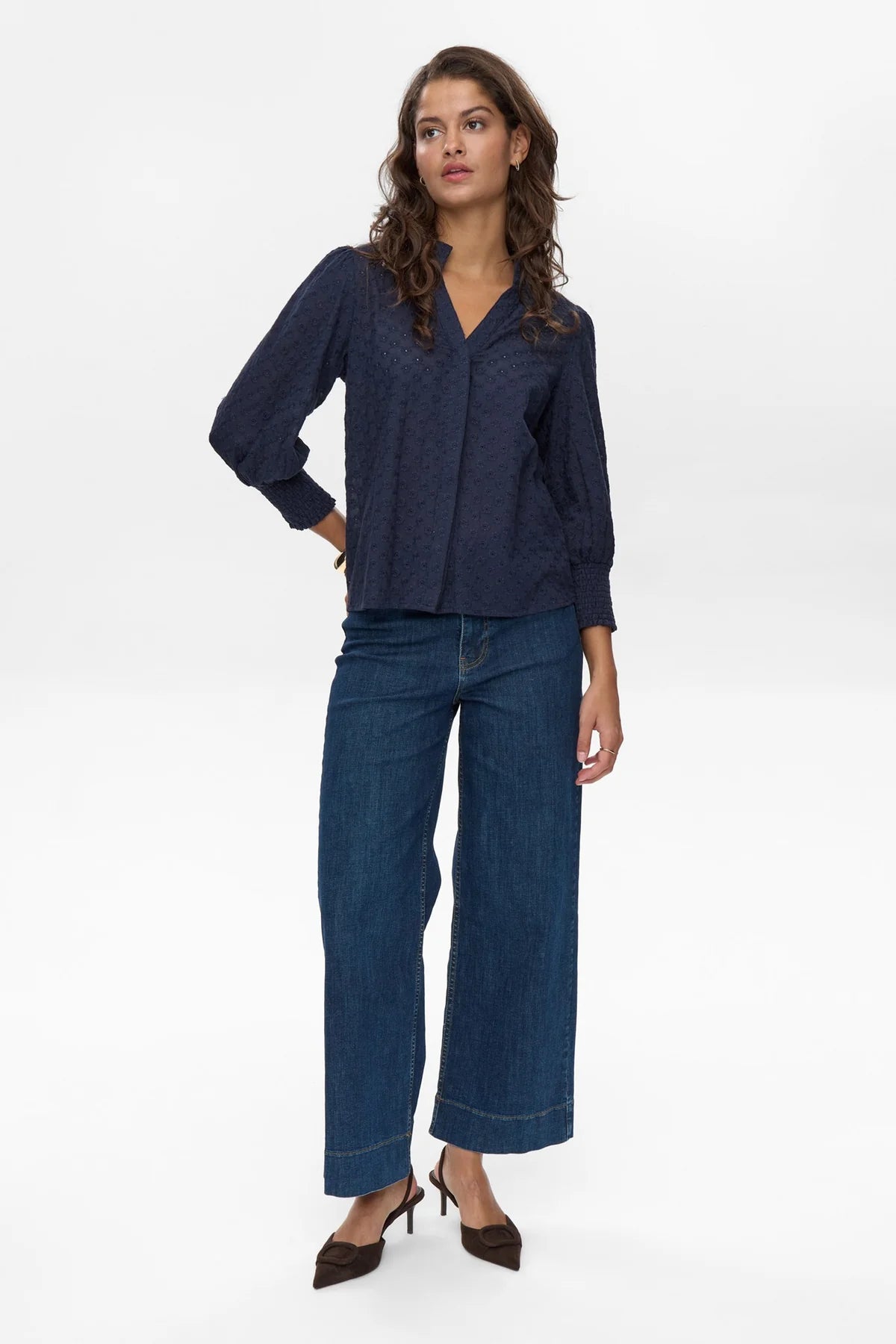Woman wearing a navy blouse and blue jeans on a white background
