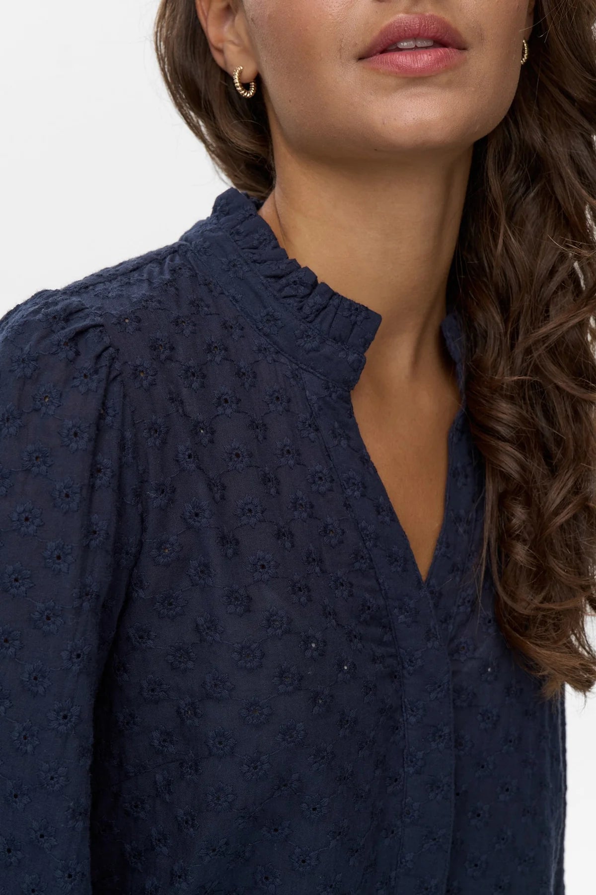 Navy blue blouse with intricate detailing worn by a model on a white background