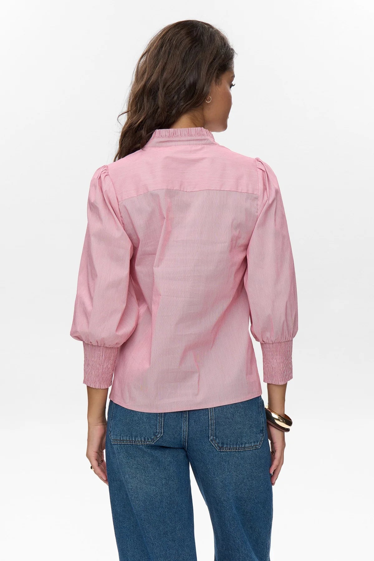 Woman wearing a pink shirt and blue jeans on a white background
