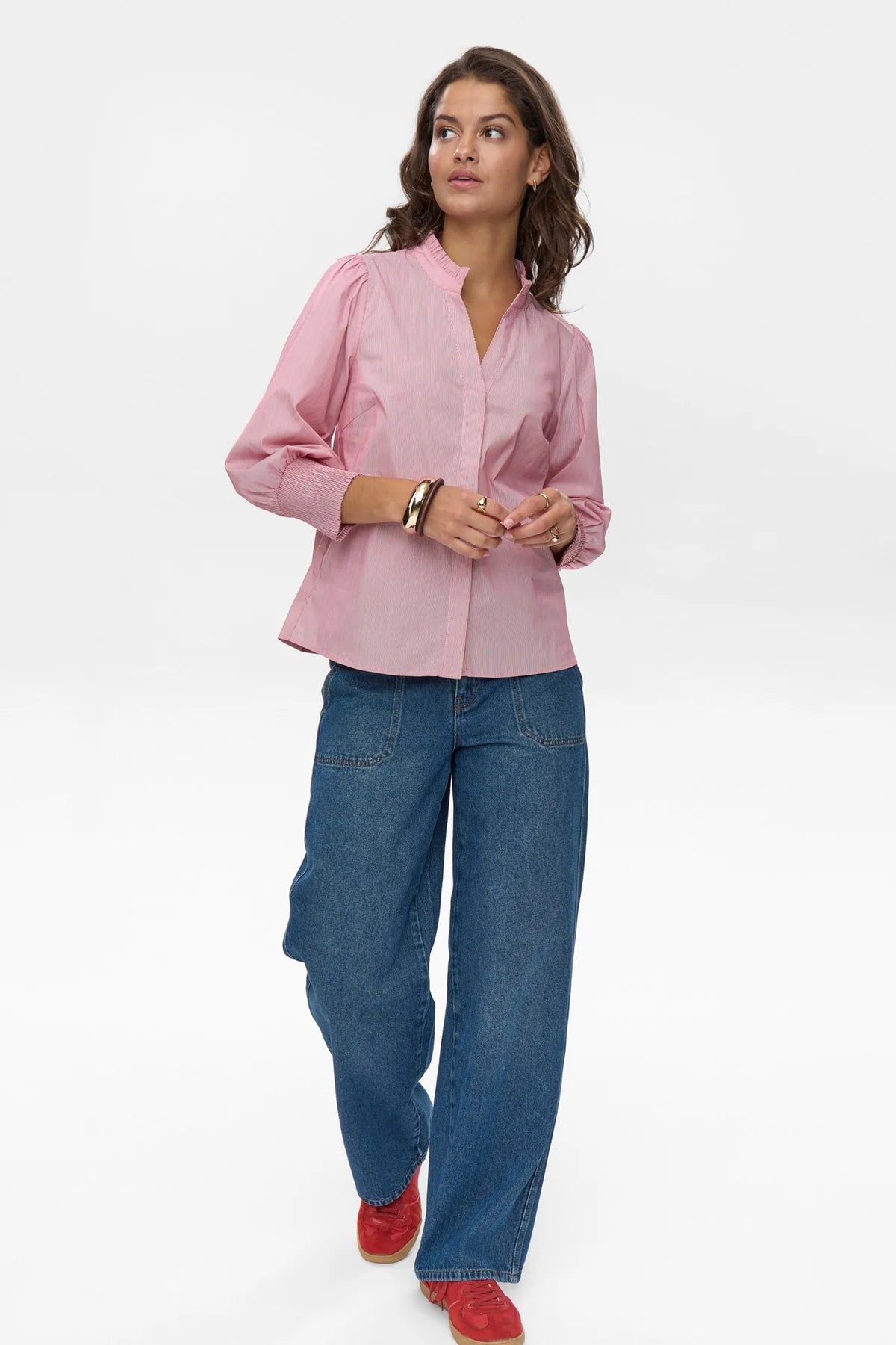 Woman wearing a pink blouse and blue jeans on a white background
