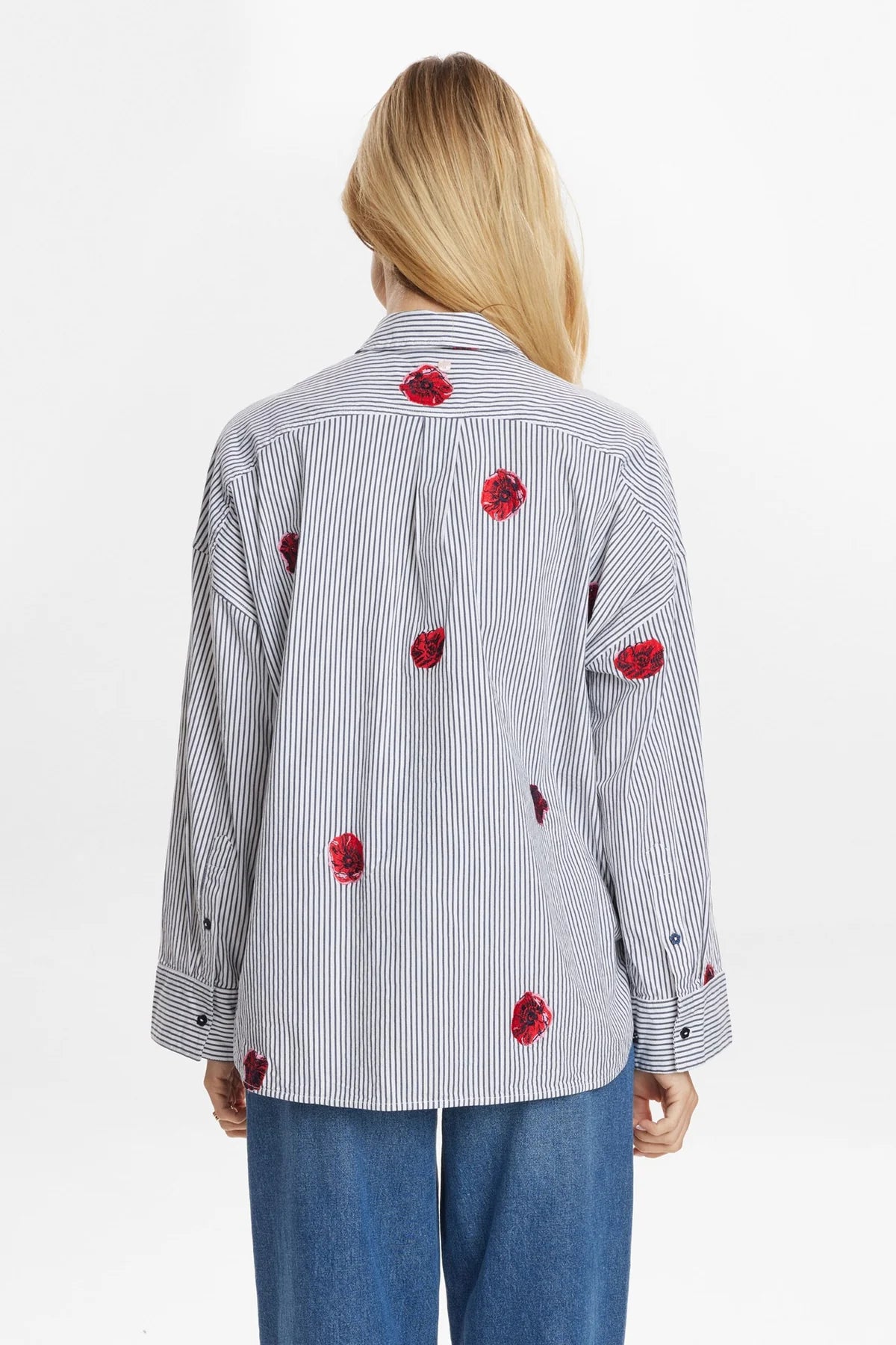 Back view of a person wearing a striped shirt with red floral patterns on a white background