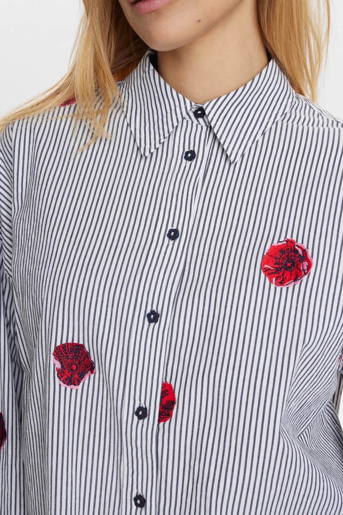 Close-up of a person wearing a black and white striped shirt with red floral patterns.
