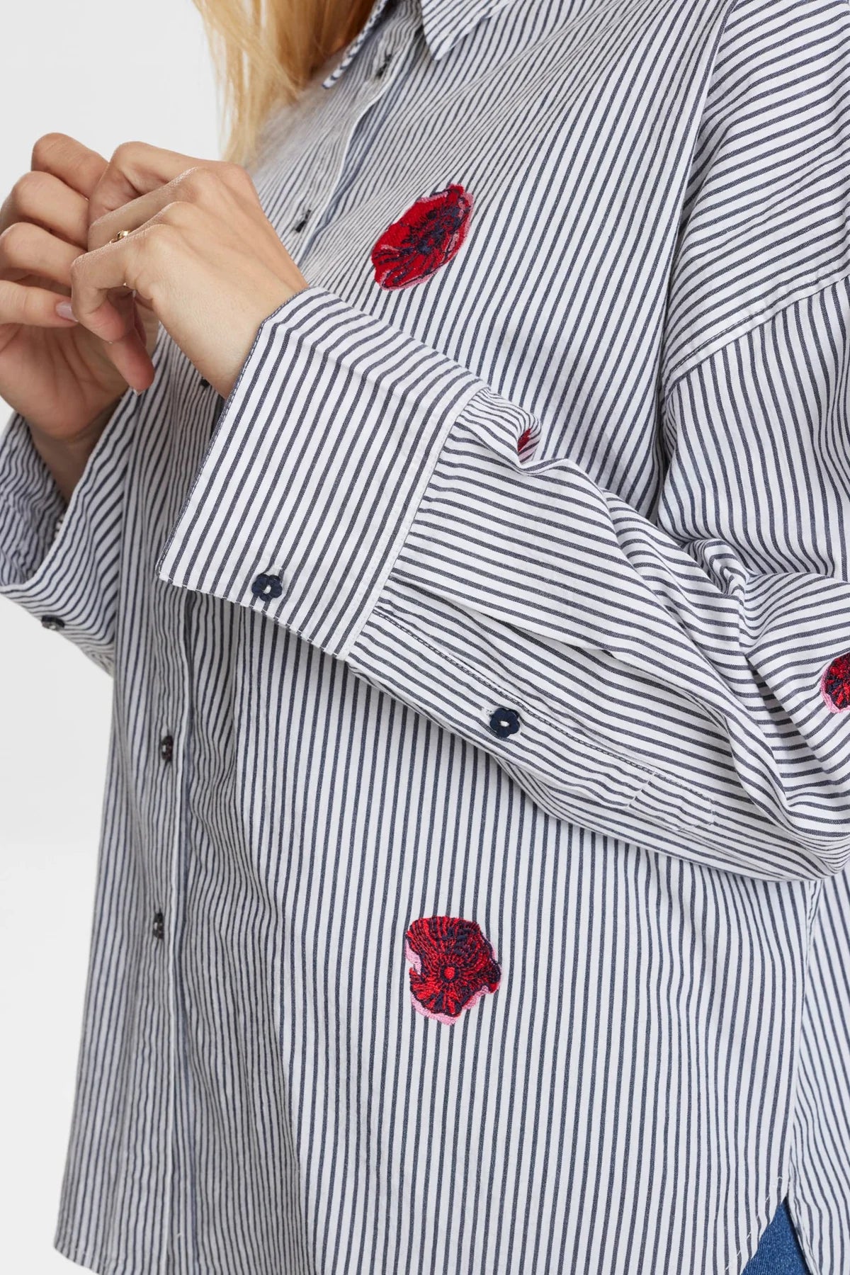 Close-up of a striped shirt with red floral embroidery on a white background