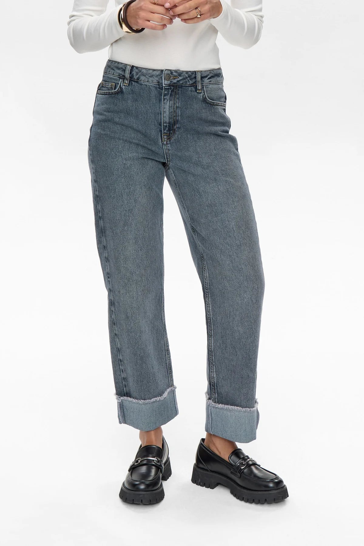 Person wearing blue jeans and black shoes on a white background
