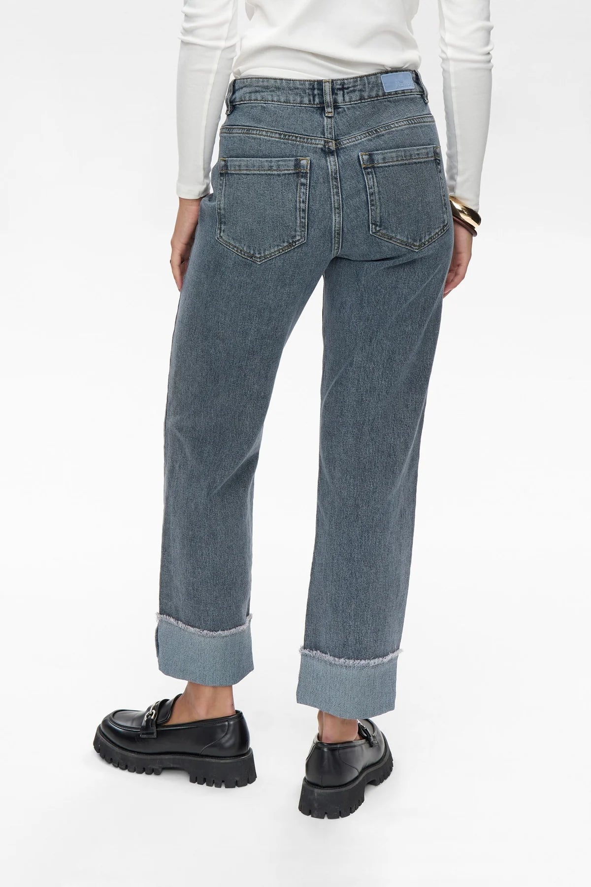 Person wearing blue jeans and black shoes on a white background