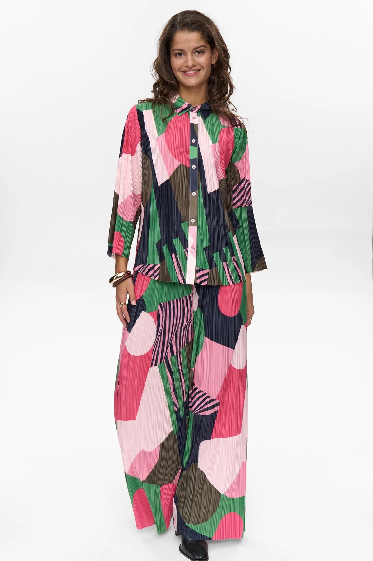 Woman wearing a colorful outfit with a patterned shirt and pants on a white background