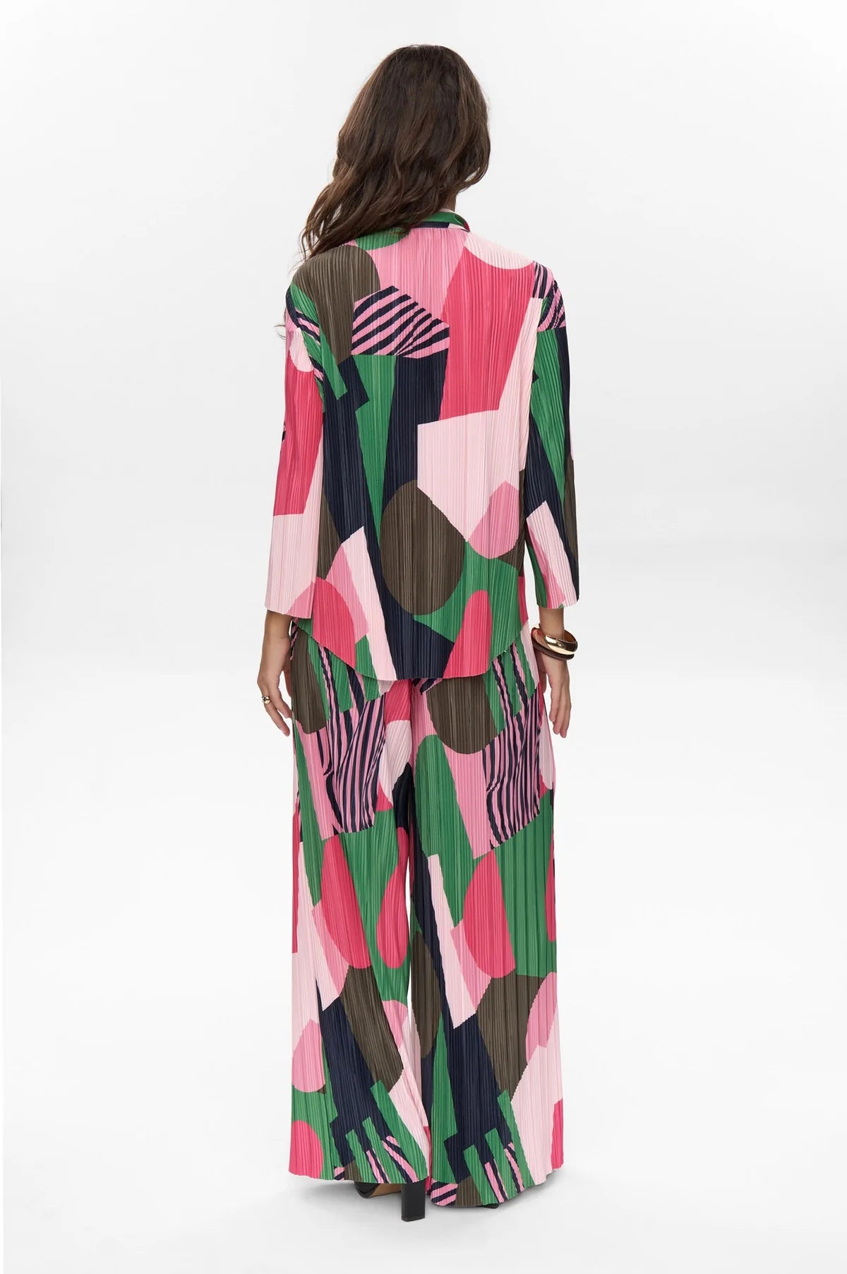 Woman wearing a colorful patterned top and trousers on a white background