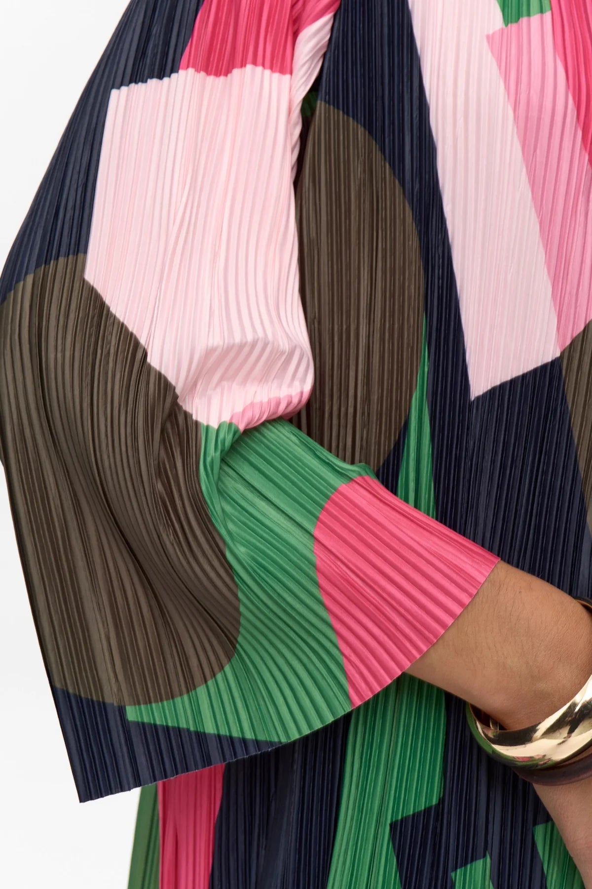 Close-up of a colorful pleated garment with pink, green, and brown patterns.