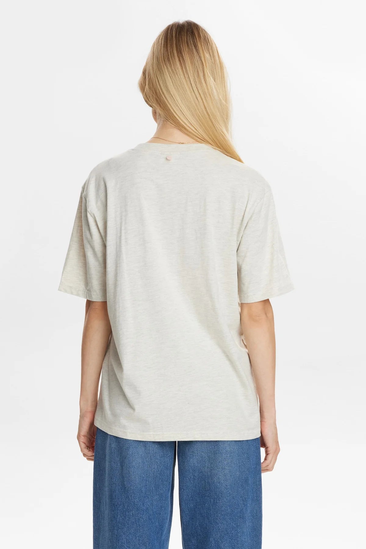 Person wearing a light-colored t-shirt and blue jeans on a white background