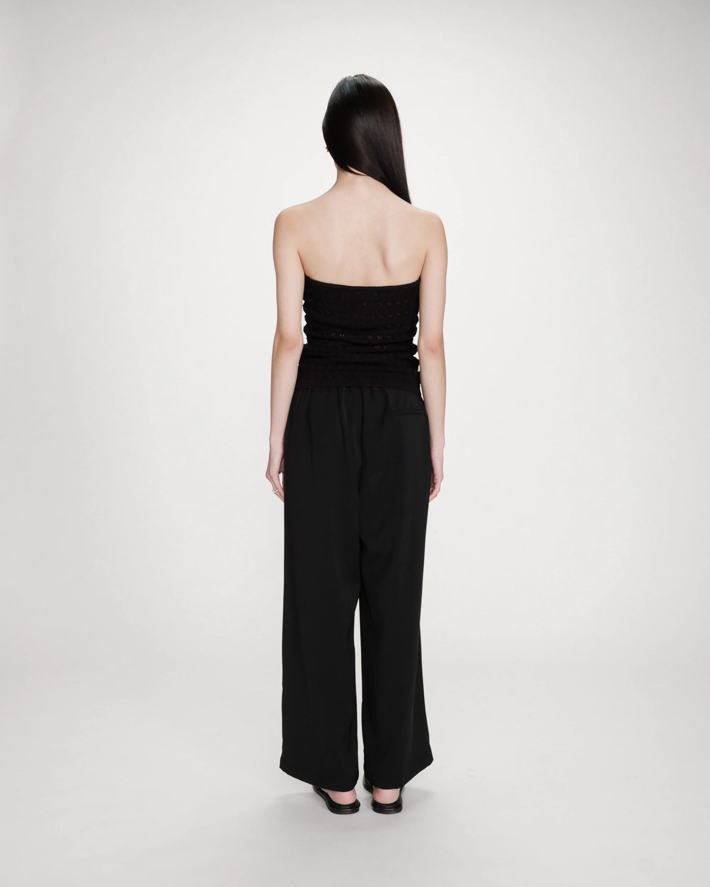 Woman wearing a black strapless jumpsuit on a white background