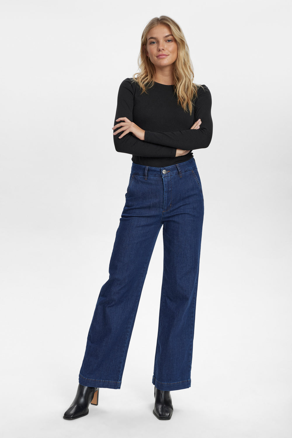 Woman wearing blue jeans and a black top on a white background