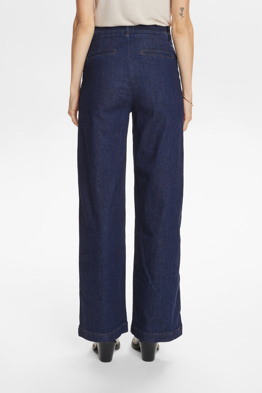 Person wearing dark blue wide-leg jeans on a white background