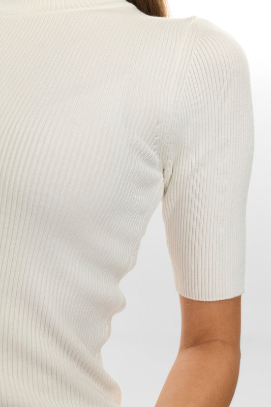 Close-up of a person wearing a white ribbed sweater on a light gray background