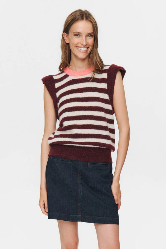 Woman wearing a striped sleeveless top and dark denim skirt on a white background
