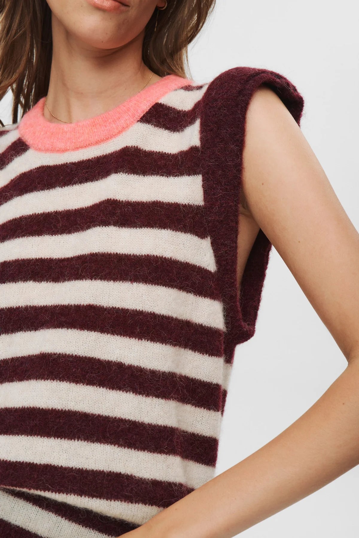 Close-up of a sleeveless striped top with a pink neckline on a plain background