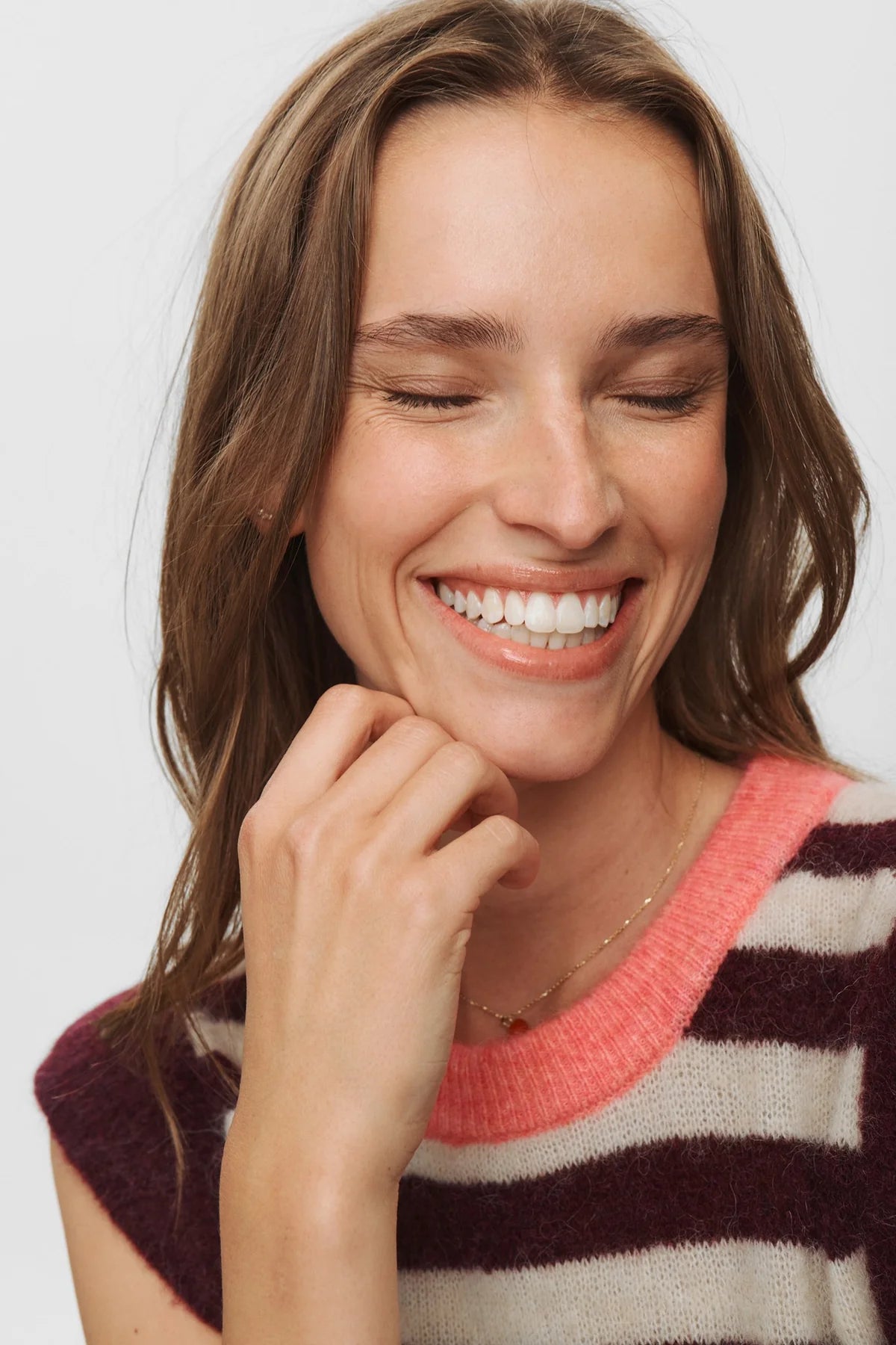Woman wearing a striped sweater with a neutral background