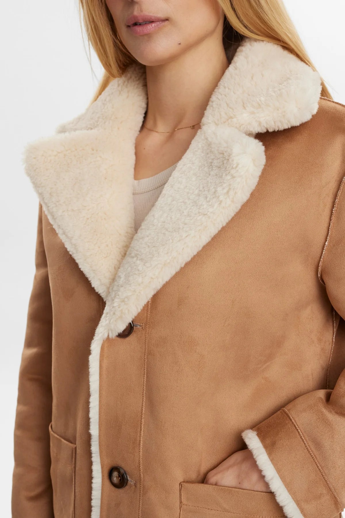 Close-up of a brown suede coat with white fur lining on a white background