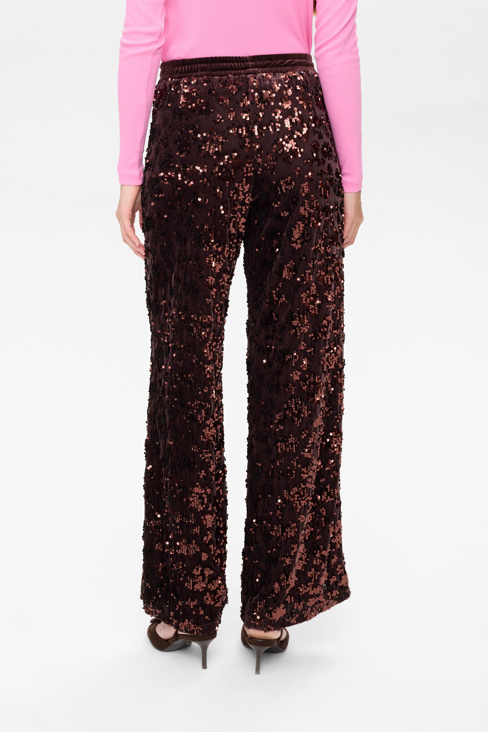 Person wearing a pair of black sequin pants on a white background