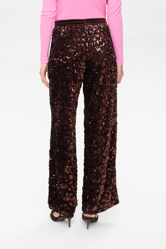 Person wearing a pair of black sequin pants on a white background