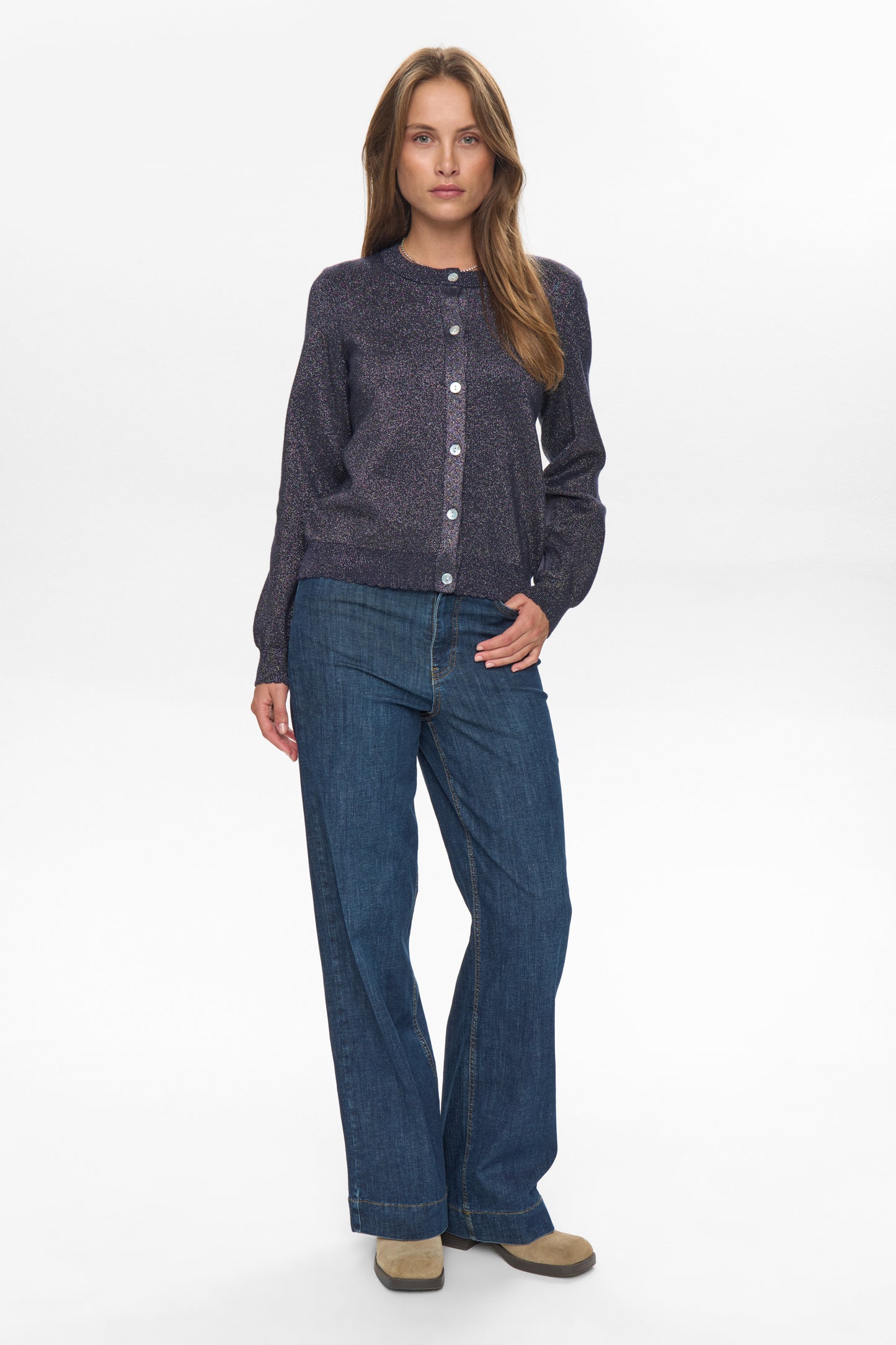 Woman wearing a dark blue cardigan and jeans on a white background