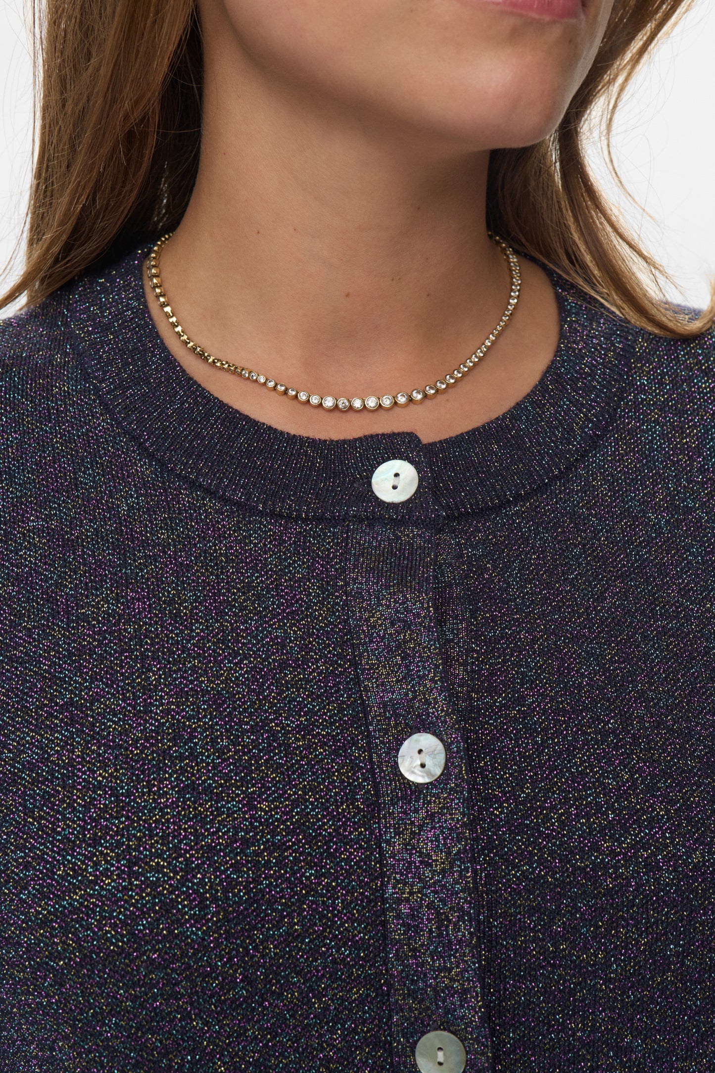 Close-up of a person wearing a dark blue textured shirt with buttons and a necklace.