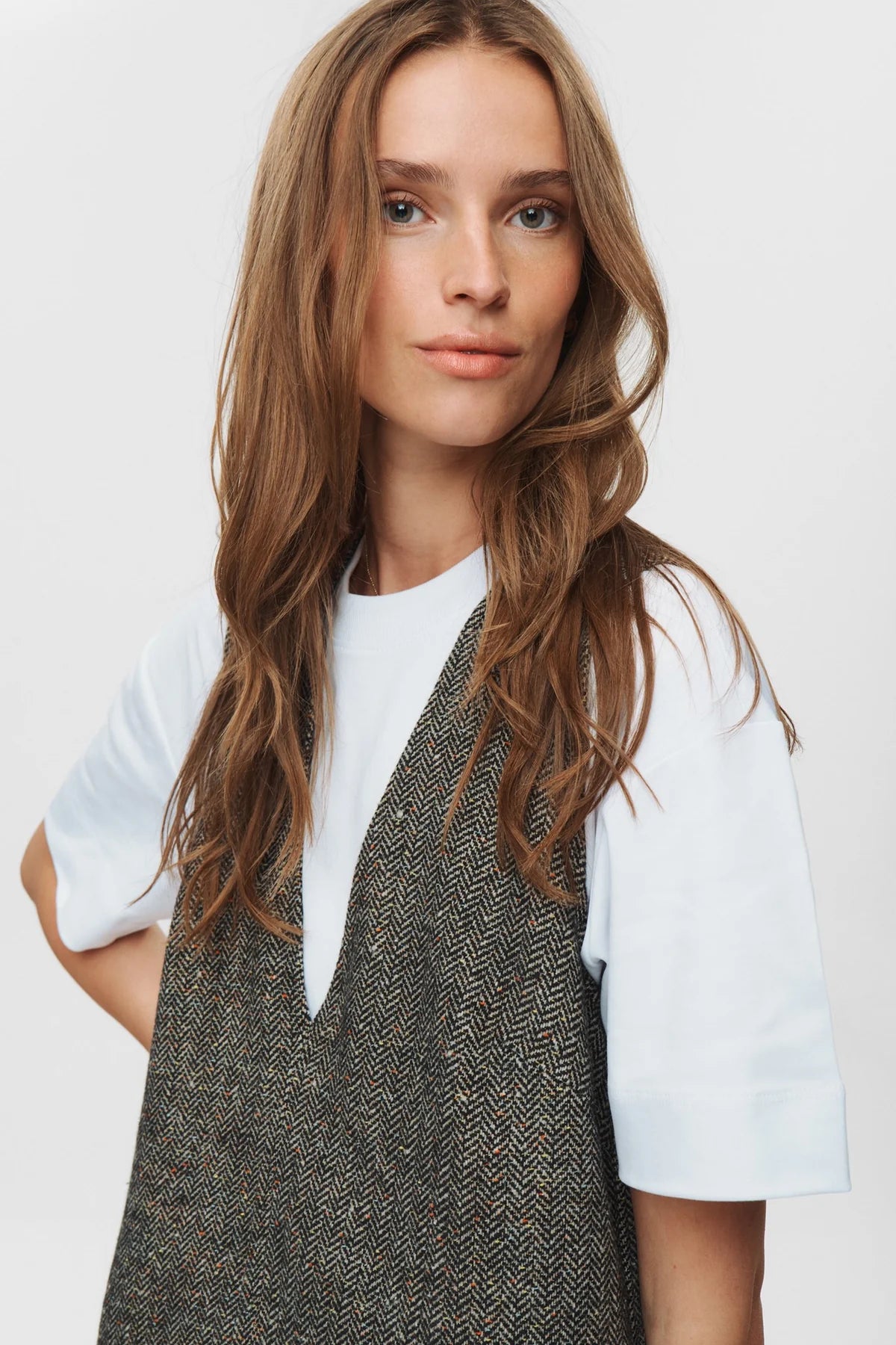 Woman wearing a patterned dress over a white shirt against a plain background