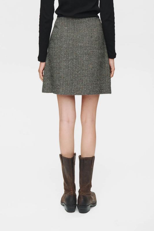 Person wearing a gray skirt with brown boots on a white background