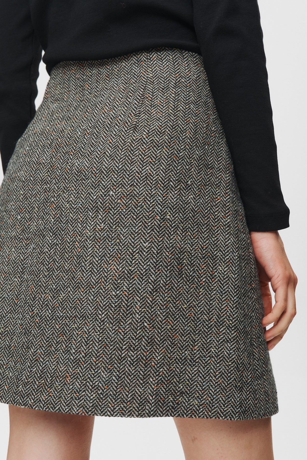 Gray herringbone patterned skirt worn by a person on a white background