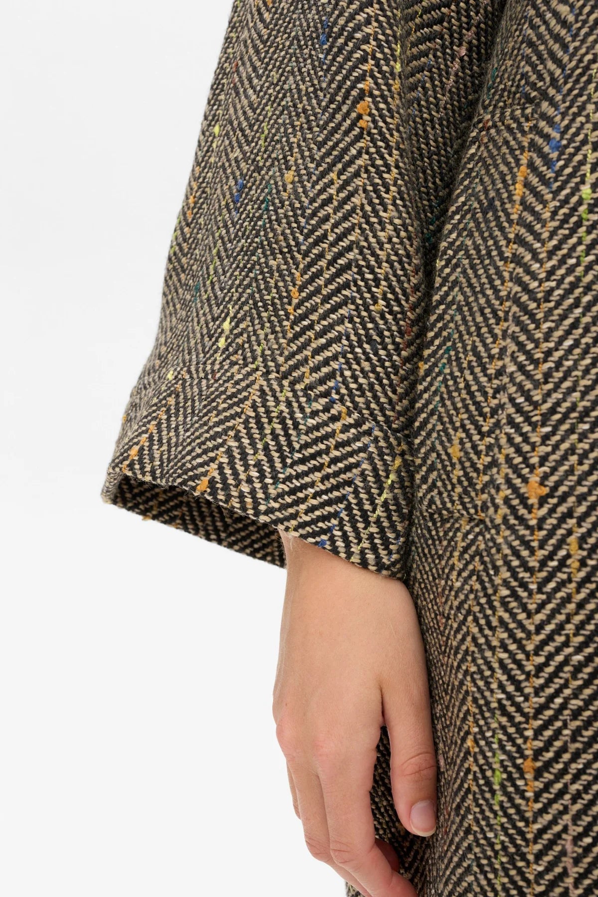 Herringbone patterned coat with a hand visible at the bottom