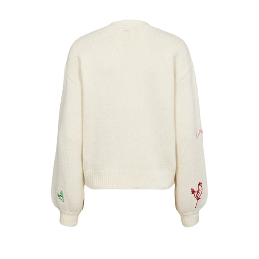 White sweater with embroidered designs on a white background
