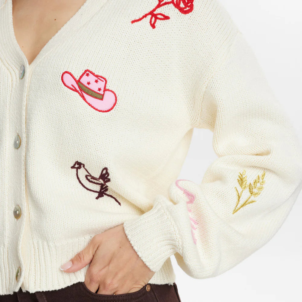 Close-up of a cream-coloured cardigan with embroidered designs on a white background