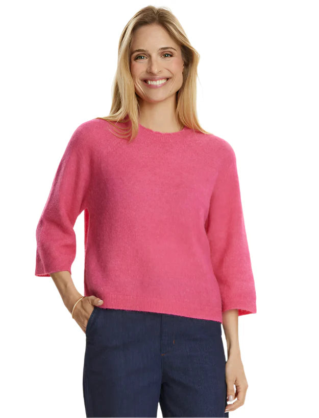 Woman standing in bright pink jumper with indigo trousers