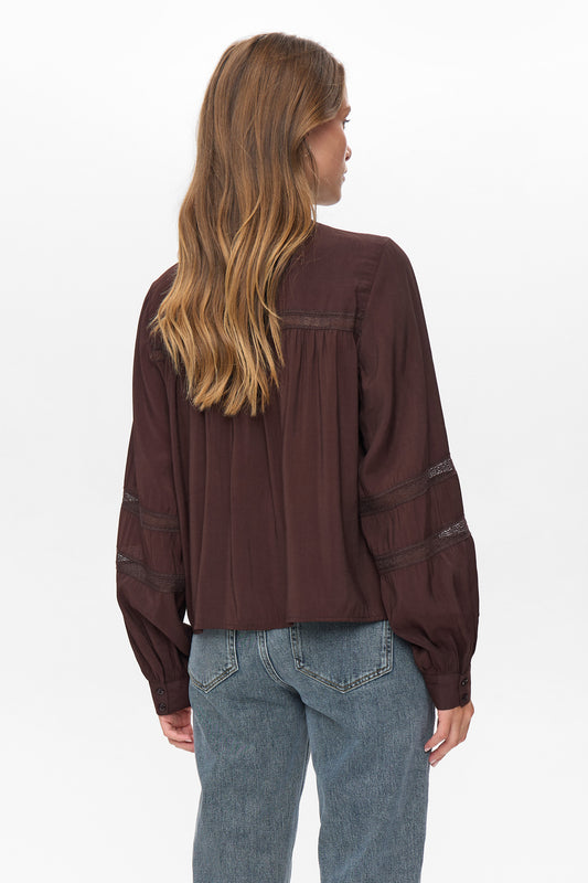 Person wearing a burgundy long-sleeve shirt and blue jeans on a white background