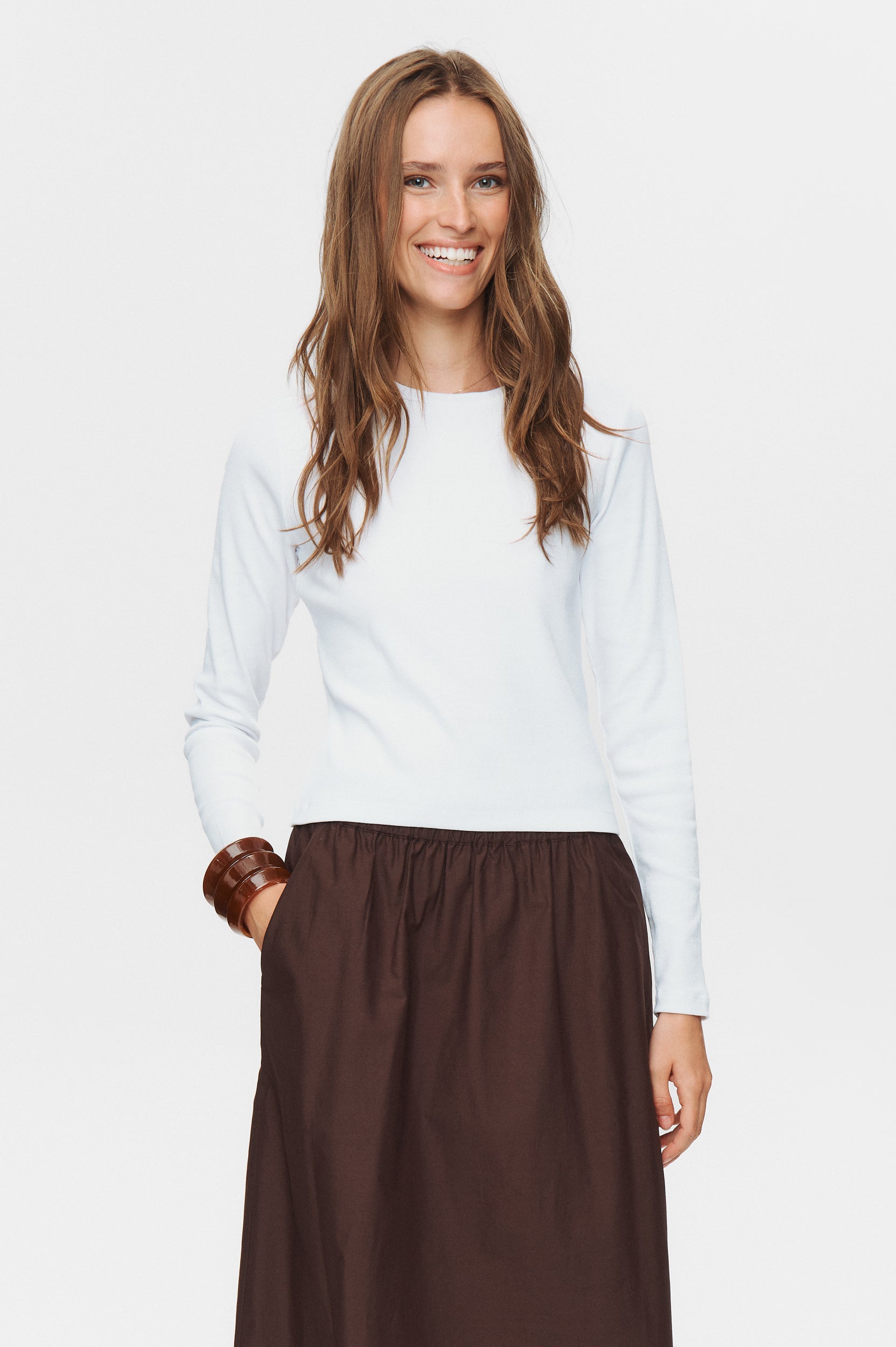 Woman wearing a white top and brown skirt on a white background