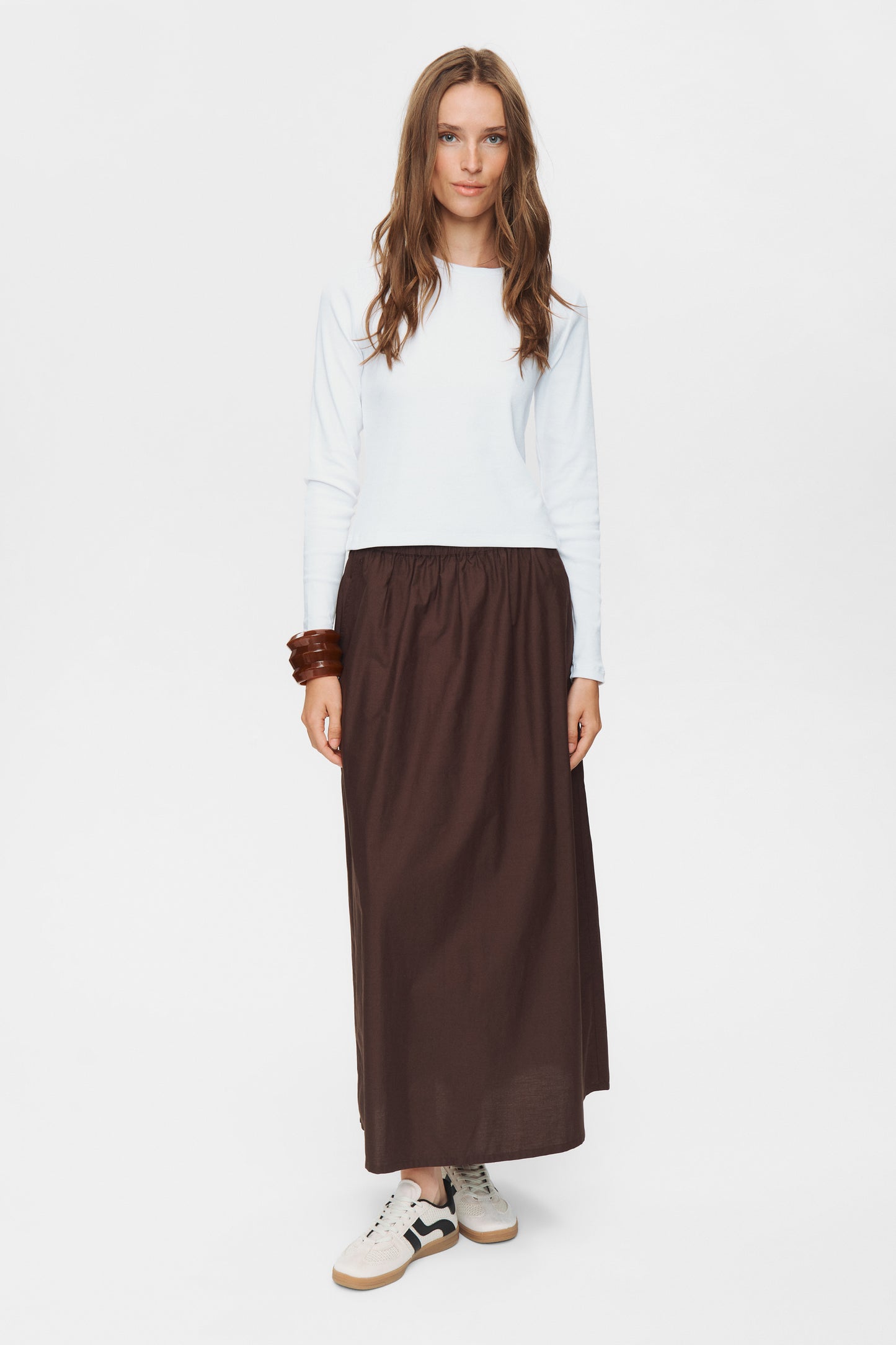 Woman wearing a white top and brown skirt on a white background