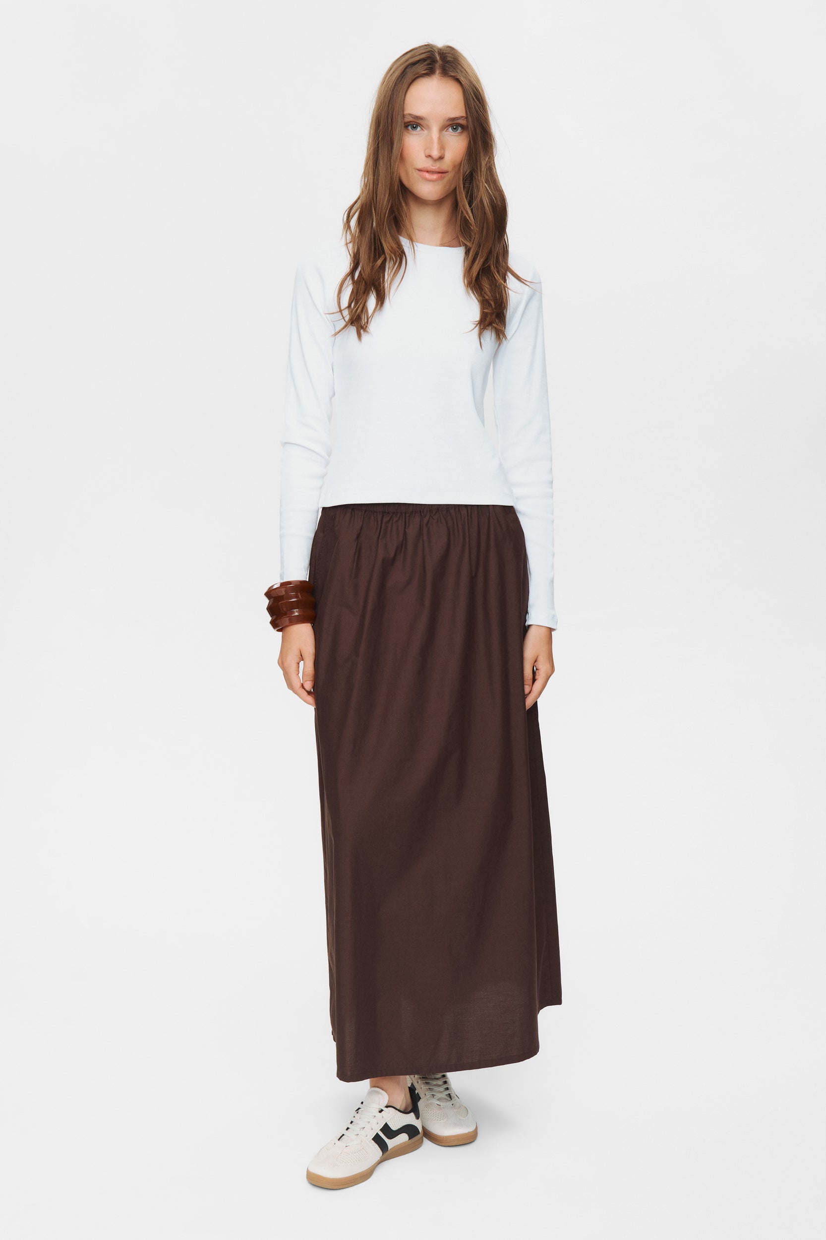 Woman wearing a white top and brown skirt on a white background