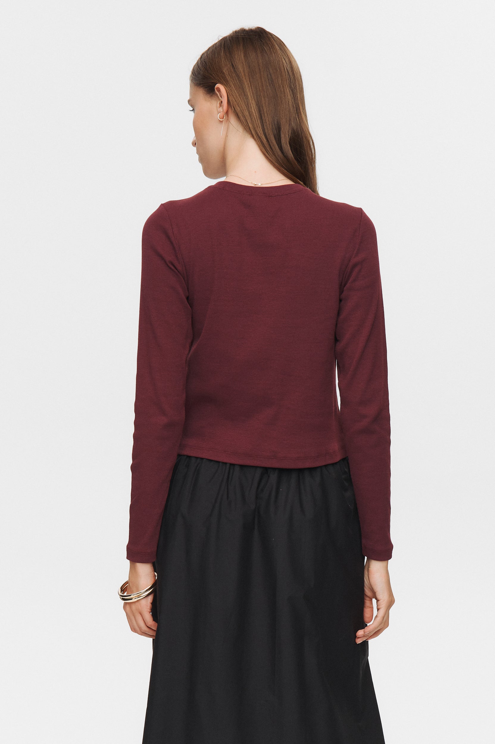 Person wearing a burgundy top and black skirt on a white background